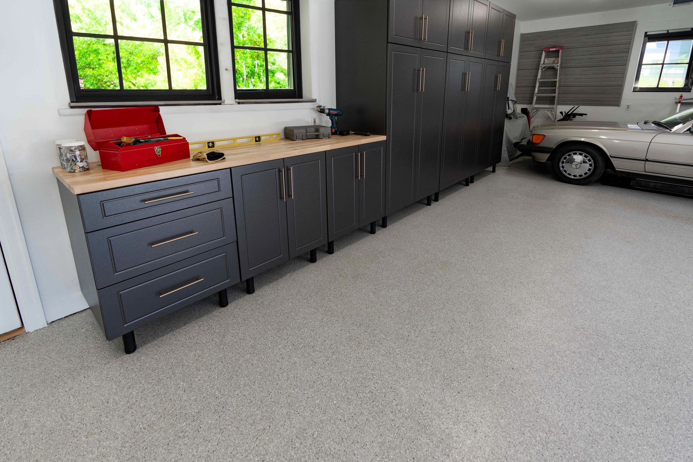 Custom garage cabinets with an integrated workbench beside a parked car